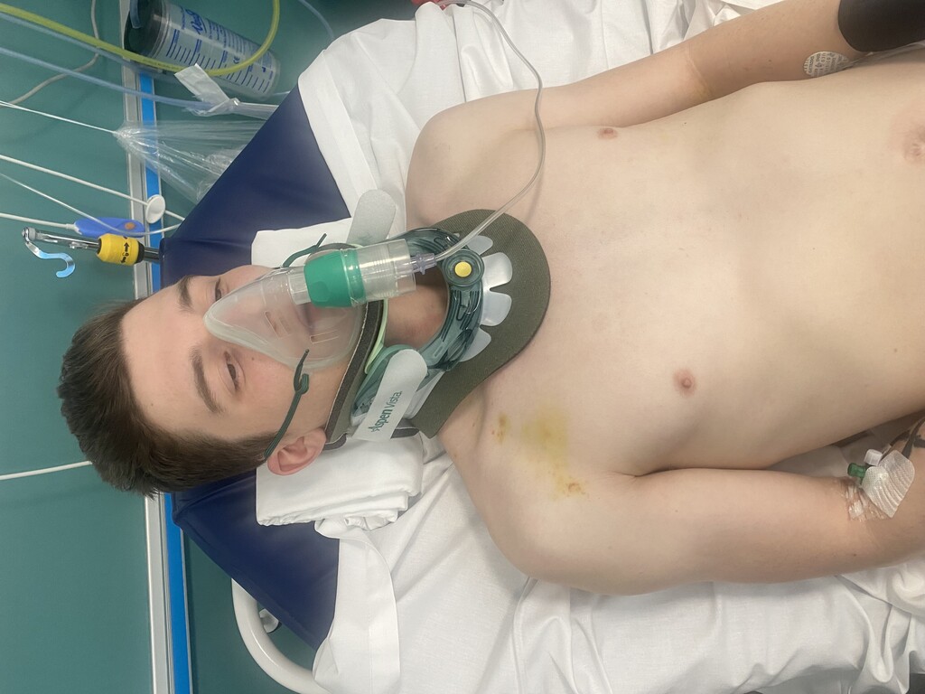 Ben in hospital with neck brace on and an ebuliser