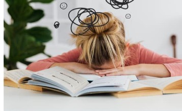what burnout is, women with her head in her hands over a book