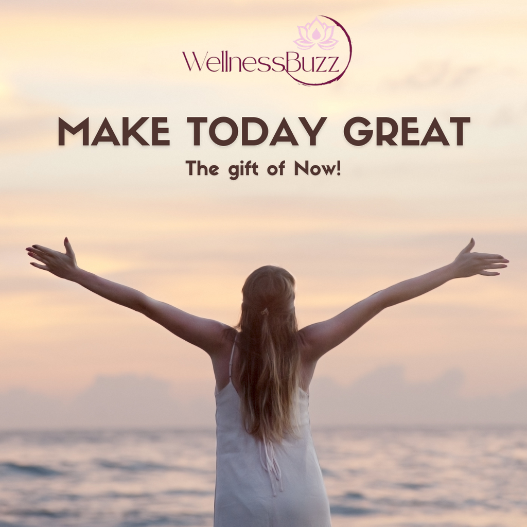 back of a women wit long hair in a white dress standing infront the sea with her hands in a V shape with the text Make yoday great The gift of now and the wellnessbuzz logo